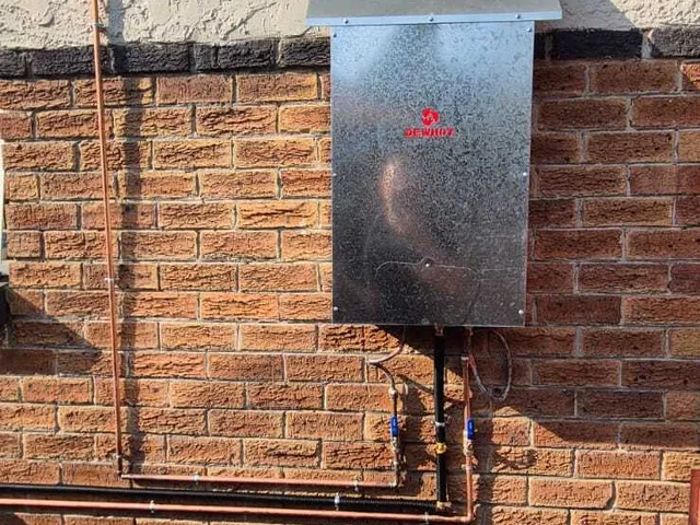Electric geyser installed on an exterior brick wall