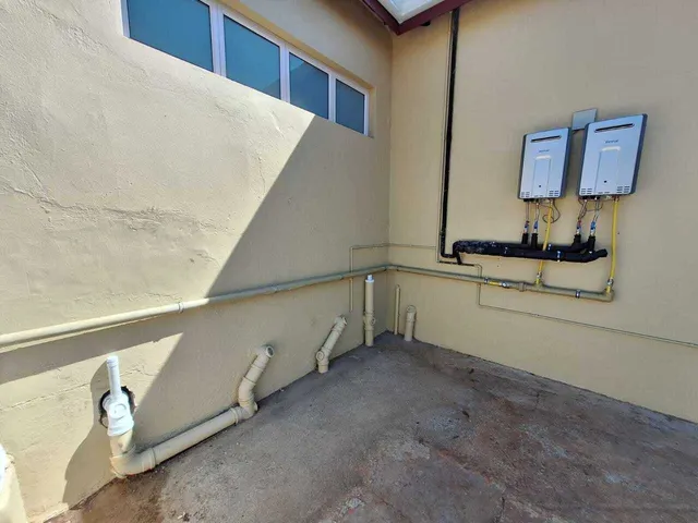 Two tankless water heaters installed on an exterior wall